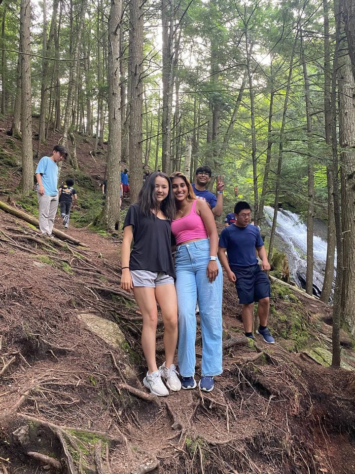 Ava and other Senators partway up a rooty forest trail in Vermont, a waterfall visible through the trees behind them.