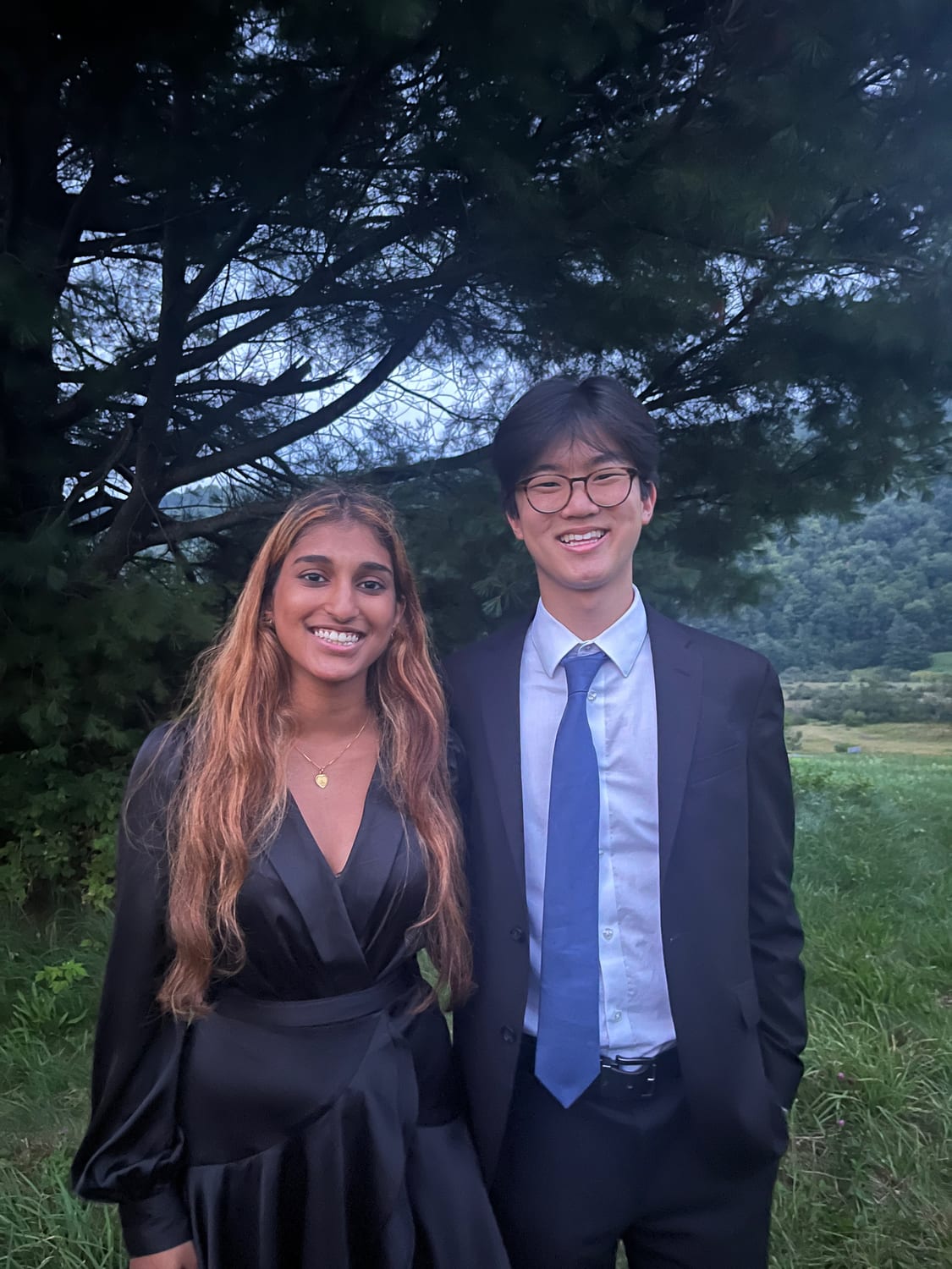 Ava and another Senator in formalwear under a pine at dusk, with the Vermont valley behind them.