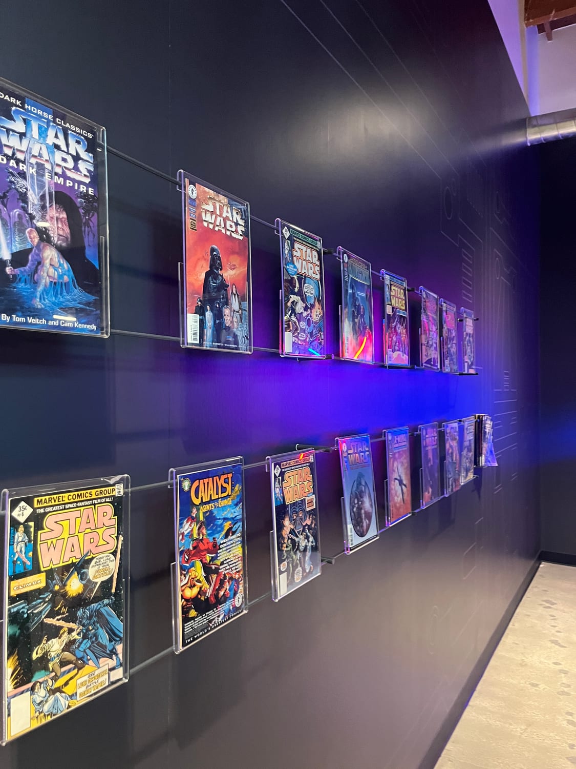 A LinkedIn office wall displaying two rows of framed vintage Star Wars comic books in acrylic mounts, lit from behind with blue and purple light.
