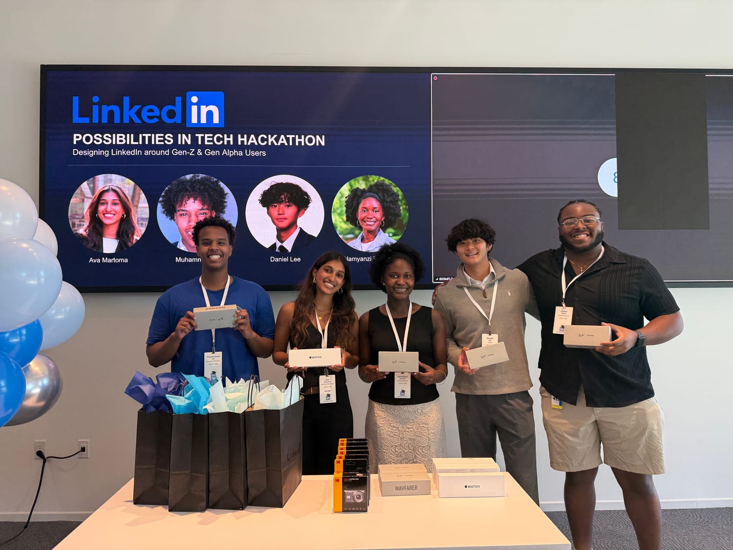 Ava and four teammates standing behind a prize table holding Apple Watch and Ray-Ban boxes, in front of a screen reading “LinkedIn — POSSIBILITIES IN TECH HACKATHON — Designing LinkedIn around Gen-Z & Gen Alpha Users” with the team’s headshots, including Ava Martoma’s.