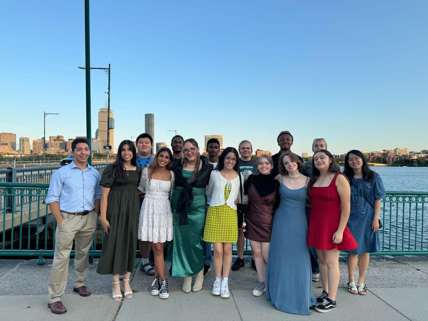 The cohort dressed up on the bridge over the Charles at golden hour, the Boston skyline behind them.
