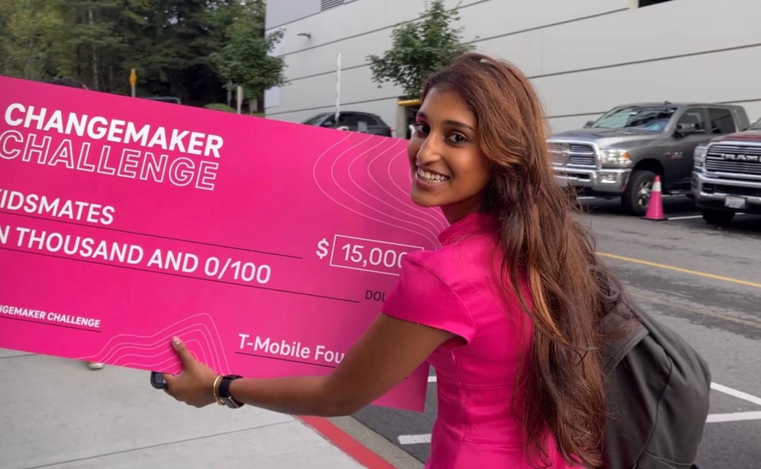 Ava carrying the giant pink $15,000 KIDSMATES check across the T-Mobile campus.