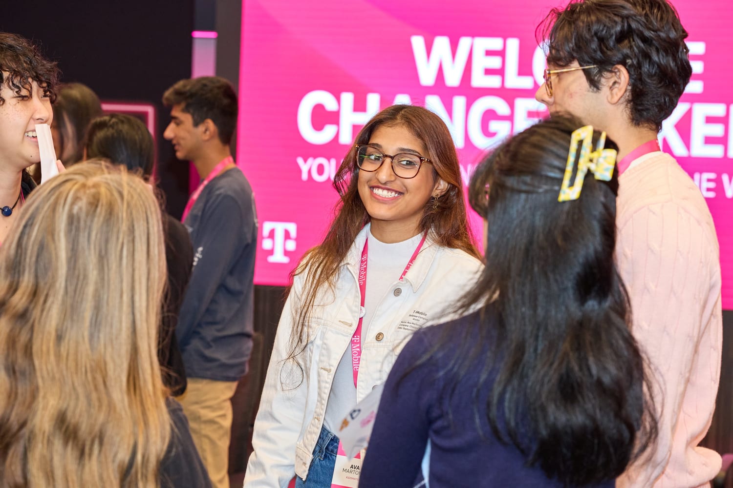 Ava talking with other participants in front of the pink “Welcome Changemakers” screen.