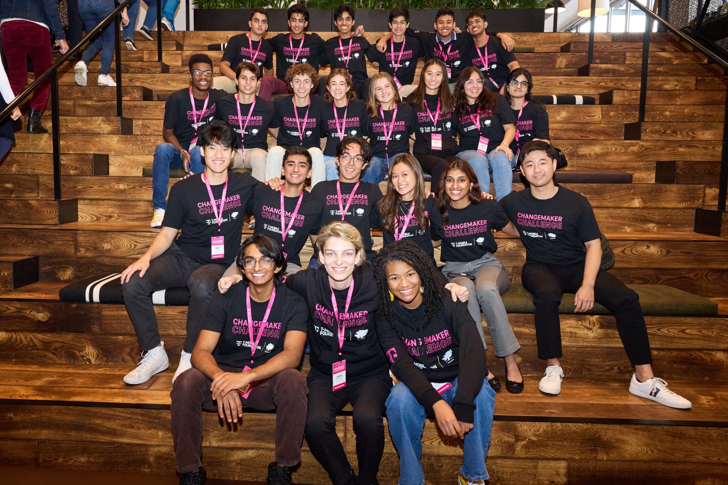 The full cohort seated together on wide wooden steps.