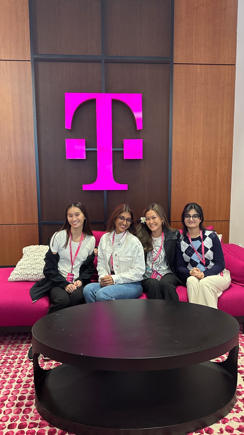 Ava and three others on a pink couch beneath a large magenta T-Mobile logo.
