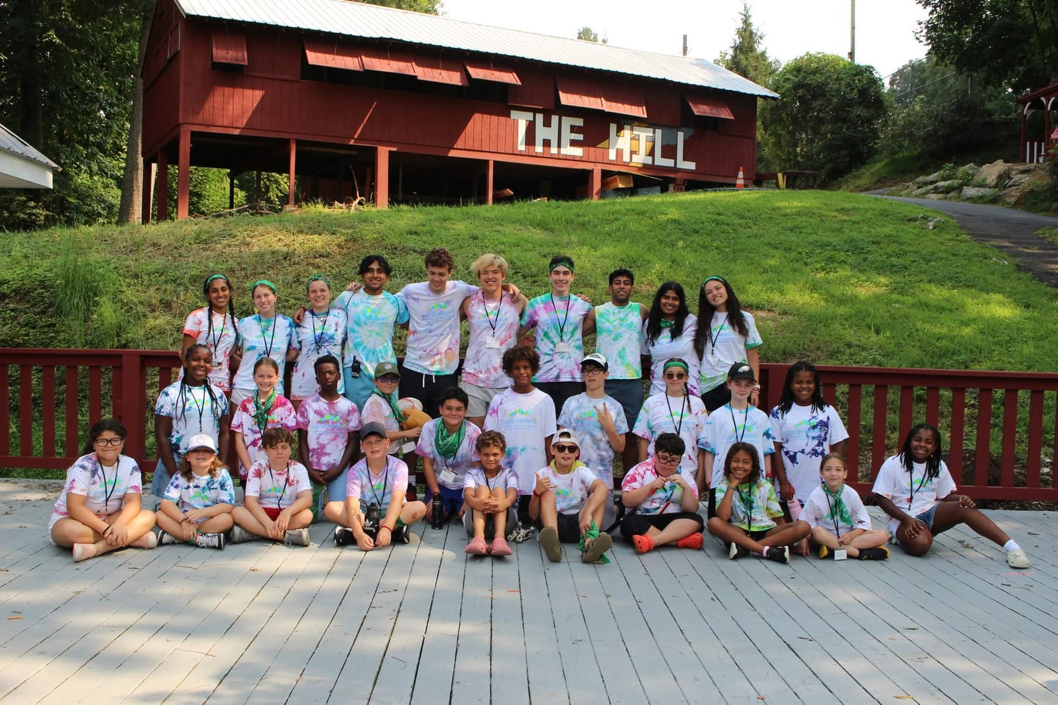 The whole unit — campers and counselors in tie-dyed Camp Kesem shirts — posed in rows on the deck in front of the red "The Hill" lodge.