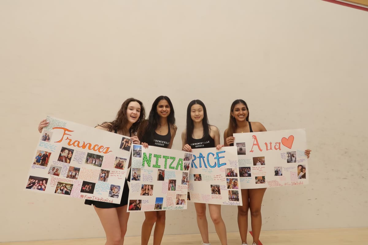 Ava and squash teammates holding handmade senior-day posters