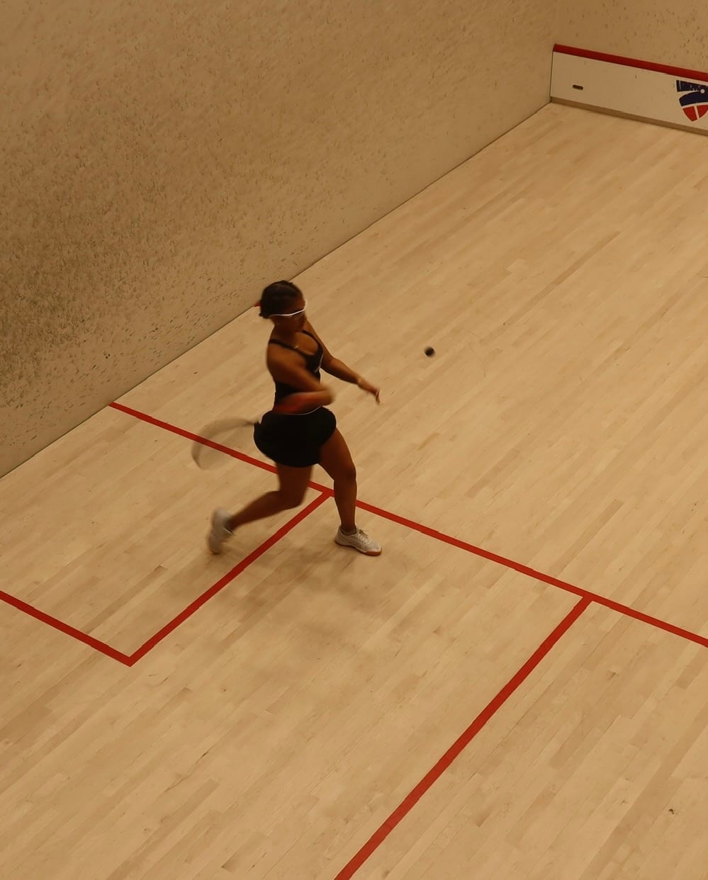Ava mid-swing during a squash match