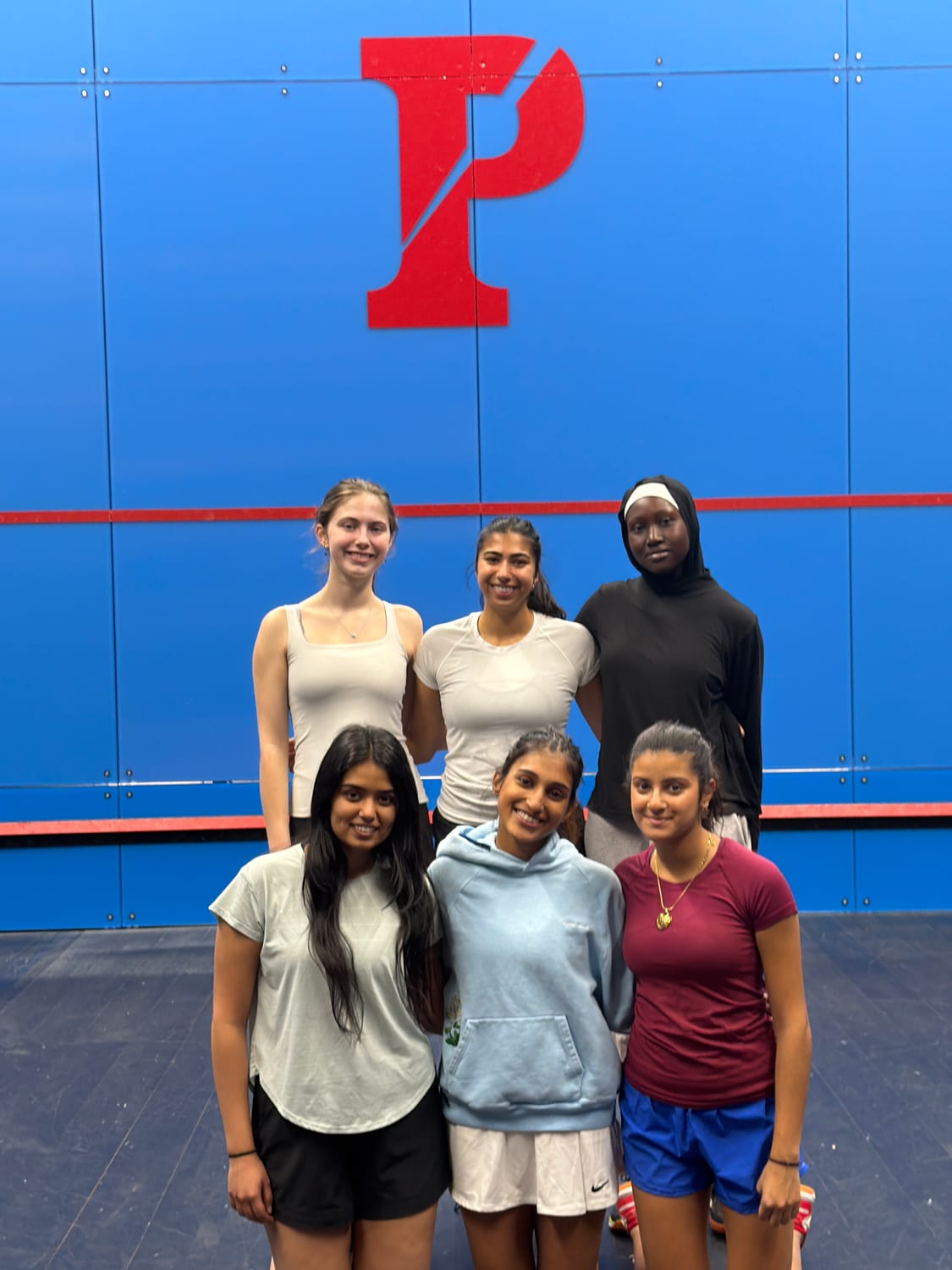 Ava with her Penn squash teammates under the Penn "P"
