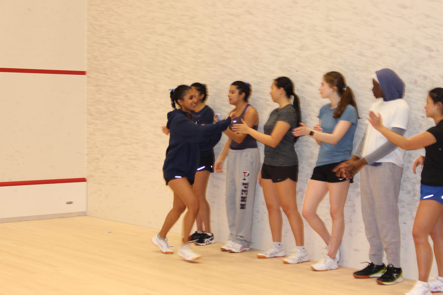 Ava's Penn squash team celebrating in a high-five line