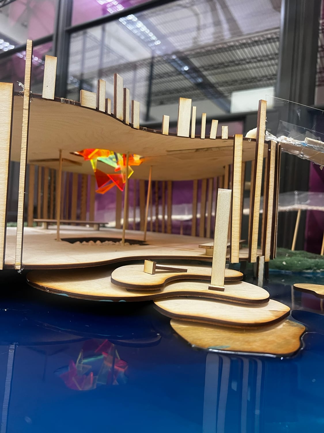 Looking in under the canopy at model eye level — slatted columns, benches, and the stained-glass fixture glowing overhead.