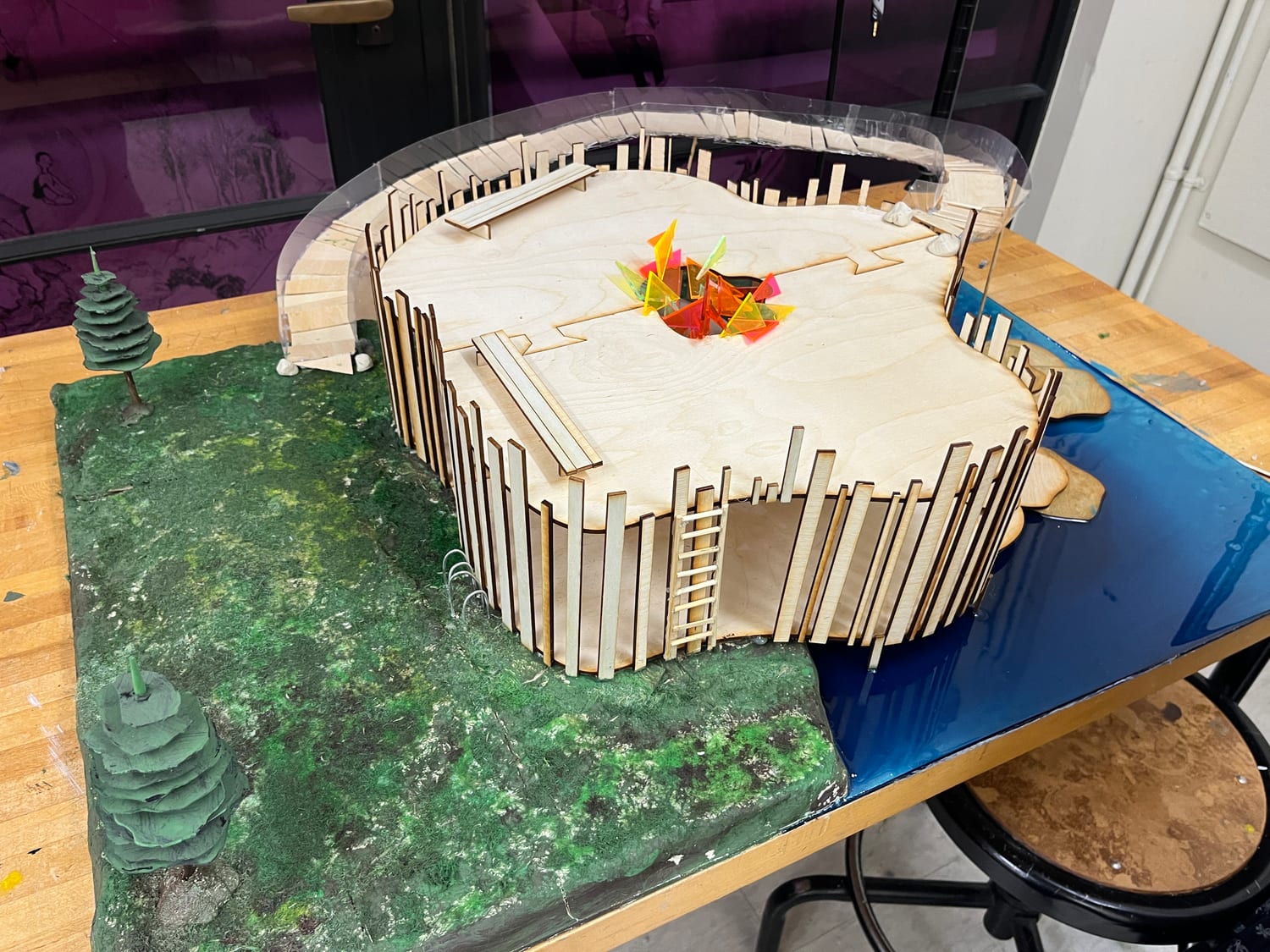 The finished model seen from the river side, its slatted walls rising off wooden stepping stones set into the water.
