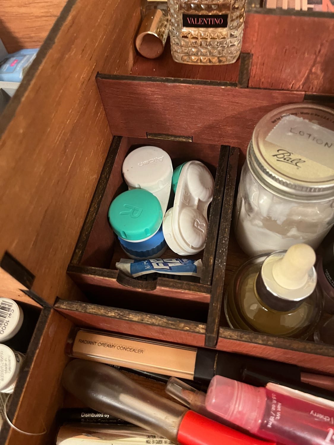 A small flip-up lidded compartment, opened to show contact-lens cases and little bottles kept out of sight.