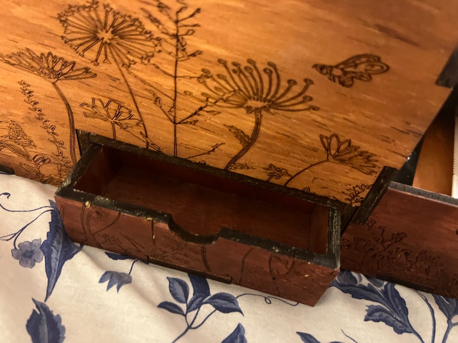 The tiny secret drawer eased open by its scalloped finger-pull, tucked into the base beneath the pyrography.