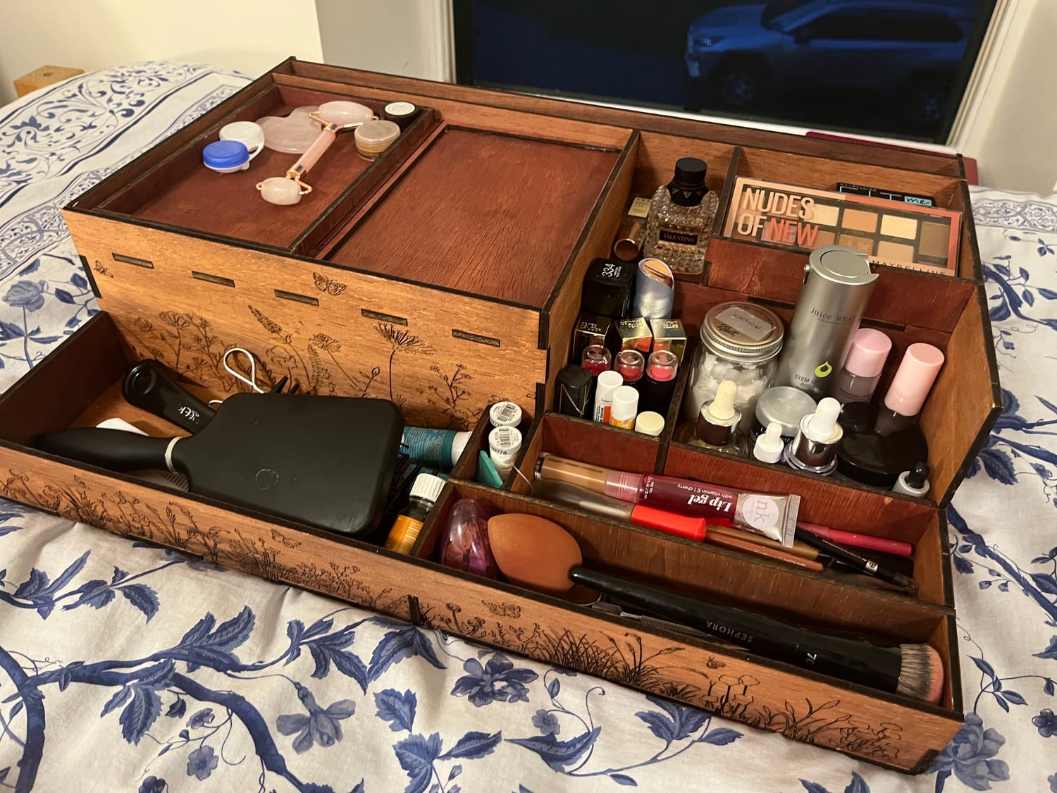 The organizer in daily use on a dresser: brushes, palettes, serums, nail polish, jewelry and hair tools each with a home in the stepped compartments.