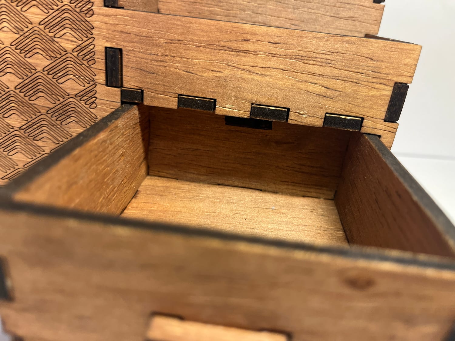 Close up on the drawer mouth — the finger joints and the charred edges left by the laser.