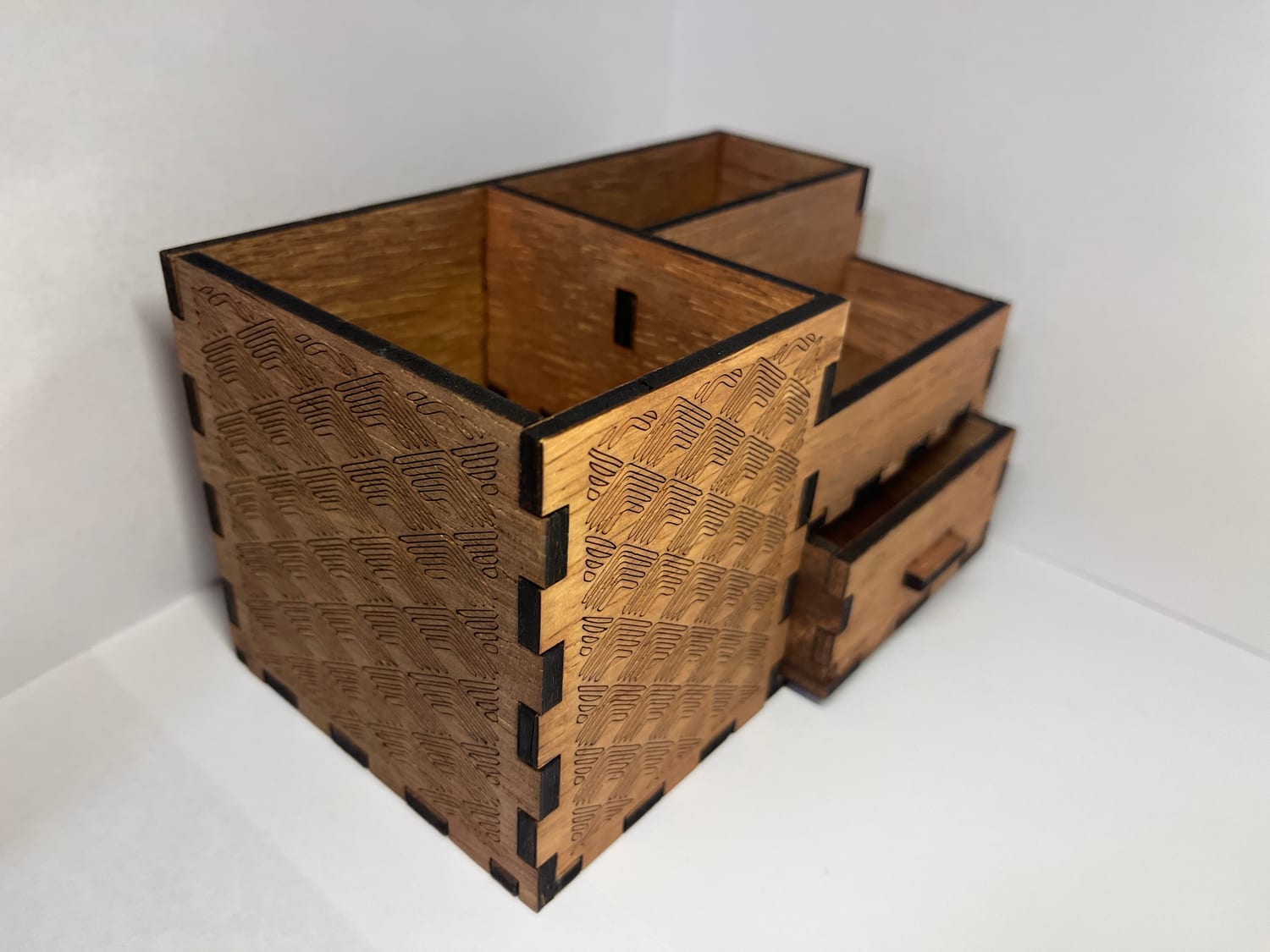 A three-quarter view with the drawer pulled out; the engraved chevron pattern runs down the end panel.