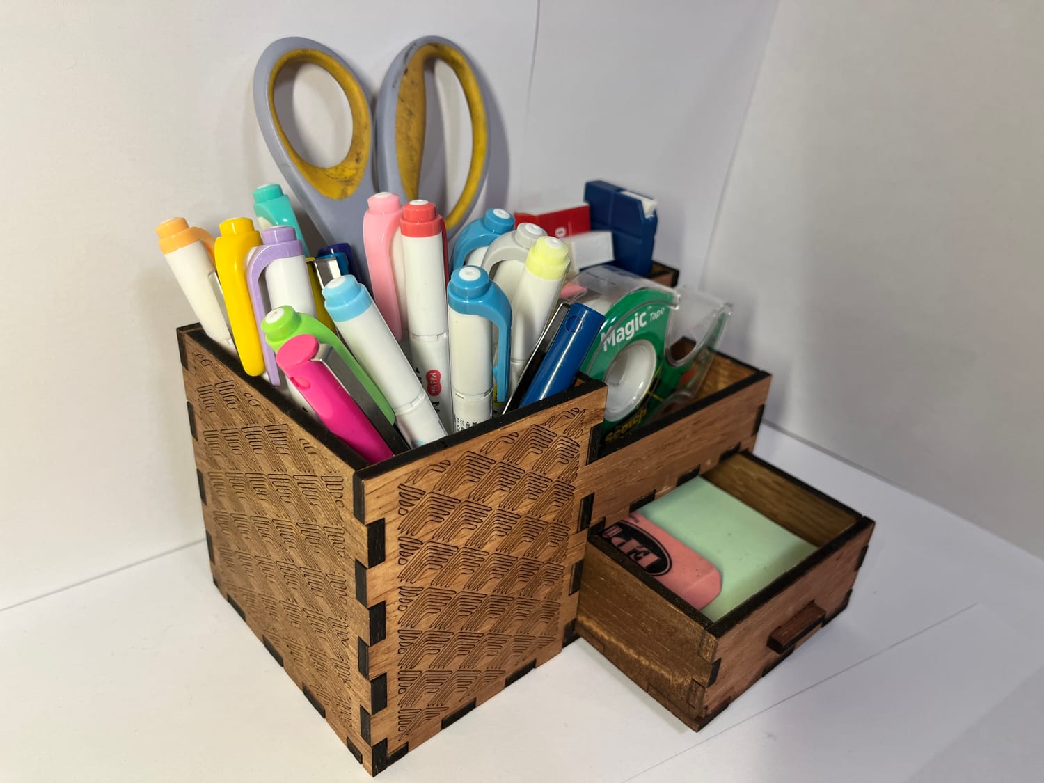 Another in-use angle: scissors and markers in the upper bay, the drawer open below with an eraser and a sticky-note pad.