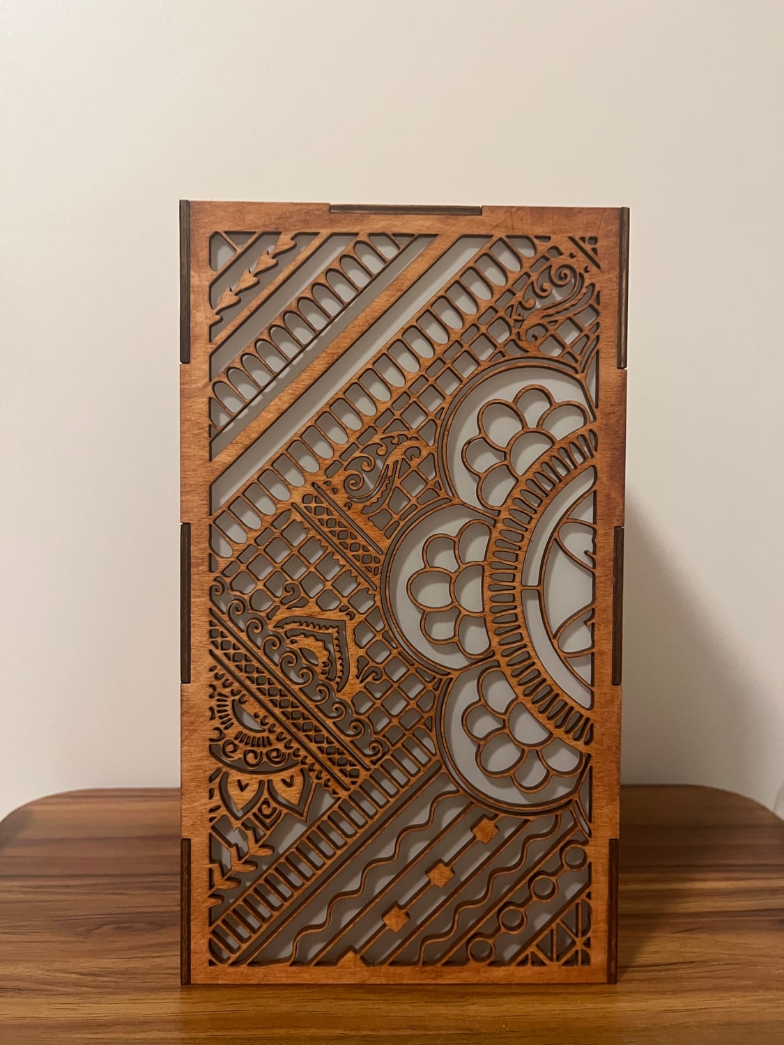 One face: diagonal geometric borders giving way to a scalloped mandala and dense paisley, vellum glowing pale behind the cut-outs.