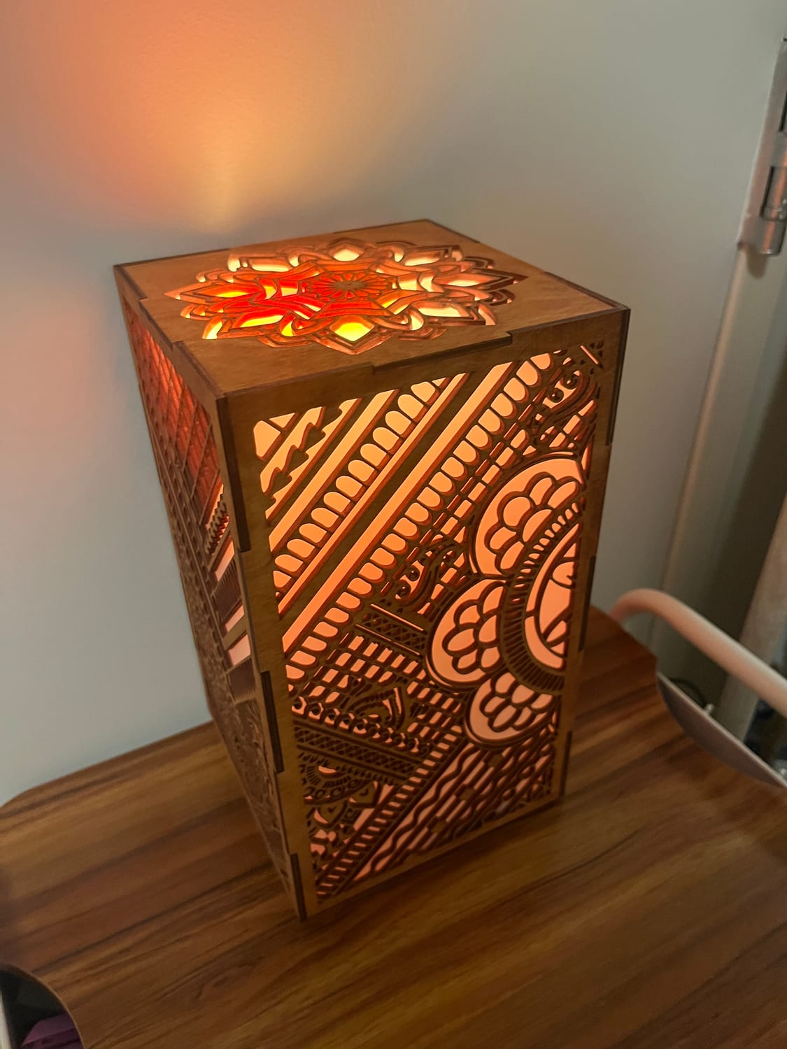 The lantern lit warm from the side, the light glowing up through the lid's mandala and throwing the fretwork into relief.