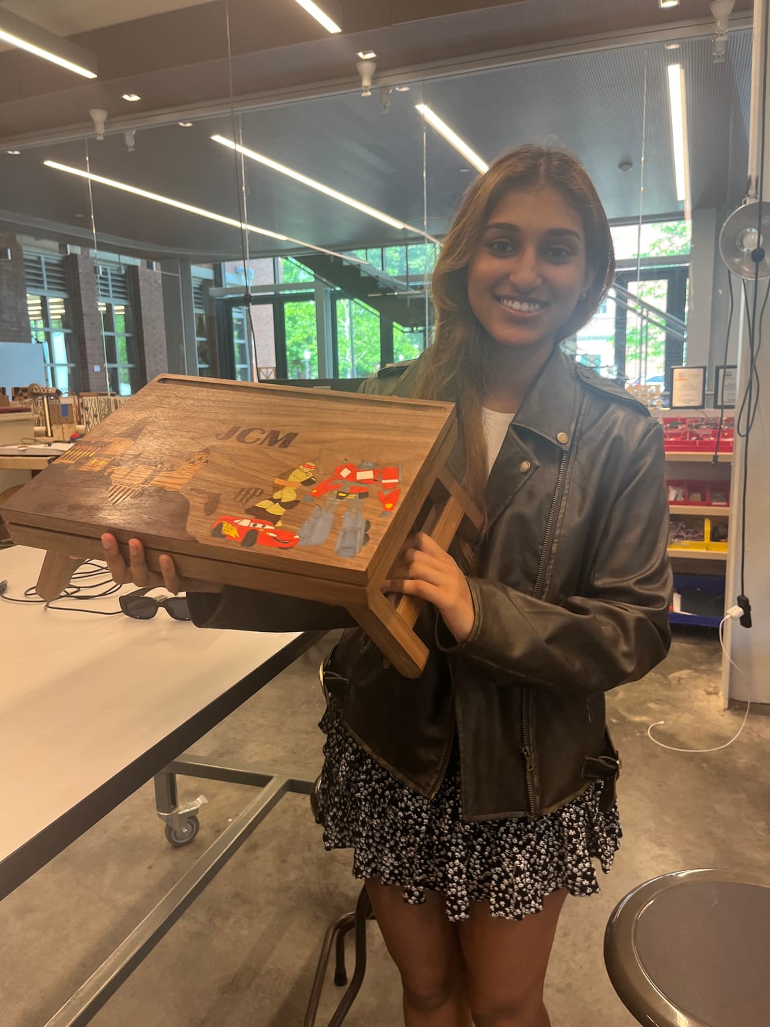 Ava holding the finished desk in the makerspace, folded legs tucked under her arm.
