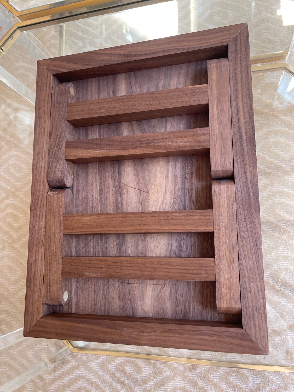 The underside at an angle: folded legs, dowel pivots, and the walnut frame rails.