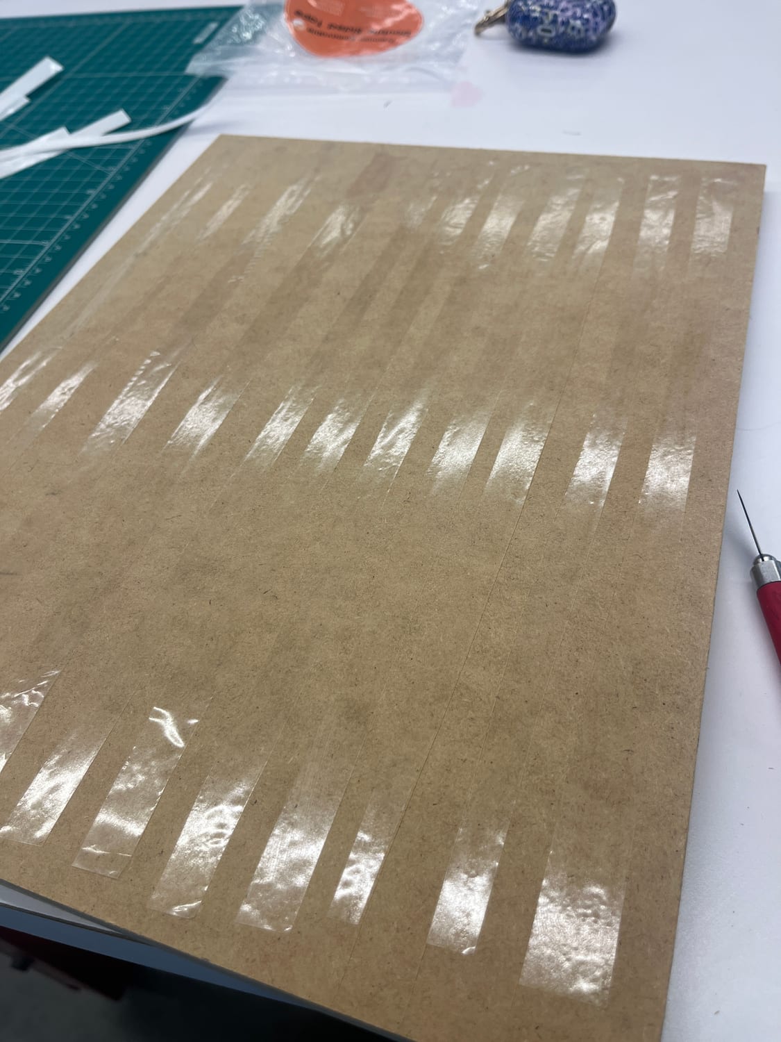 More veneer tape webbing the sheet so the packet stays flat and intact through the laser.