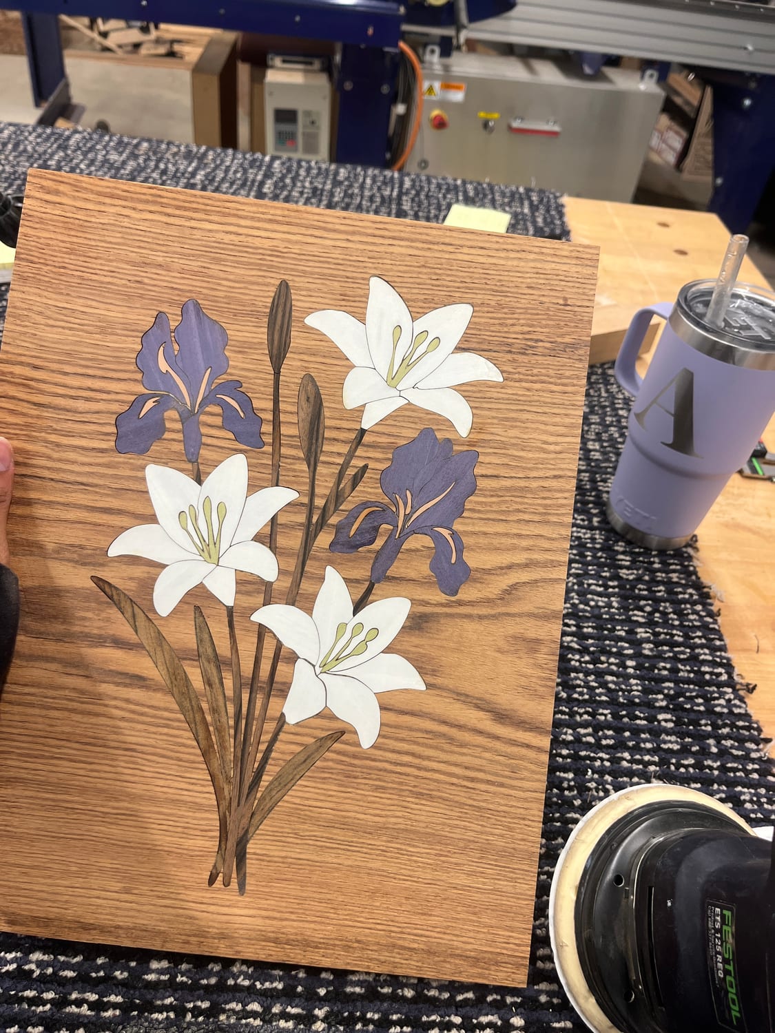 The finished bouquet: white lilies with green stamens, two purple irises and a bud, walnut stems and leaves, all inlaid into an oak ground.