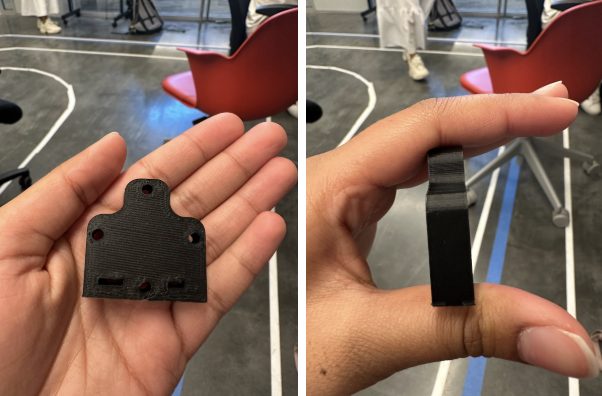 Two of the 3D-printed parts in hand — a drilled motor/servo mounting bracket and a small printed clip.
