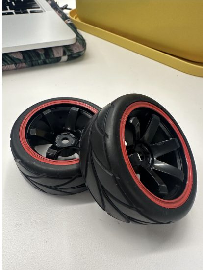 The treaded rubber RC tires on black rims with red bead rings.
